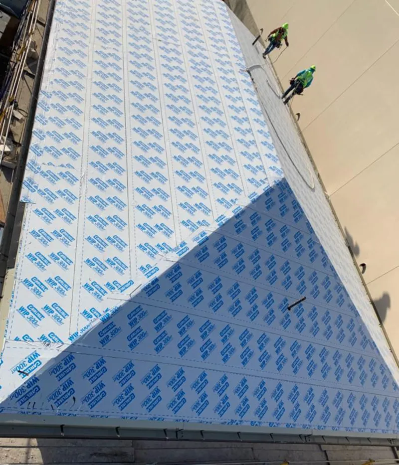 Professional roofers installing underlayment on a metal roof in Dighton